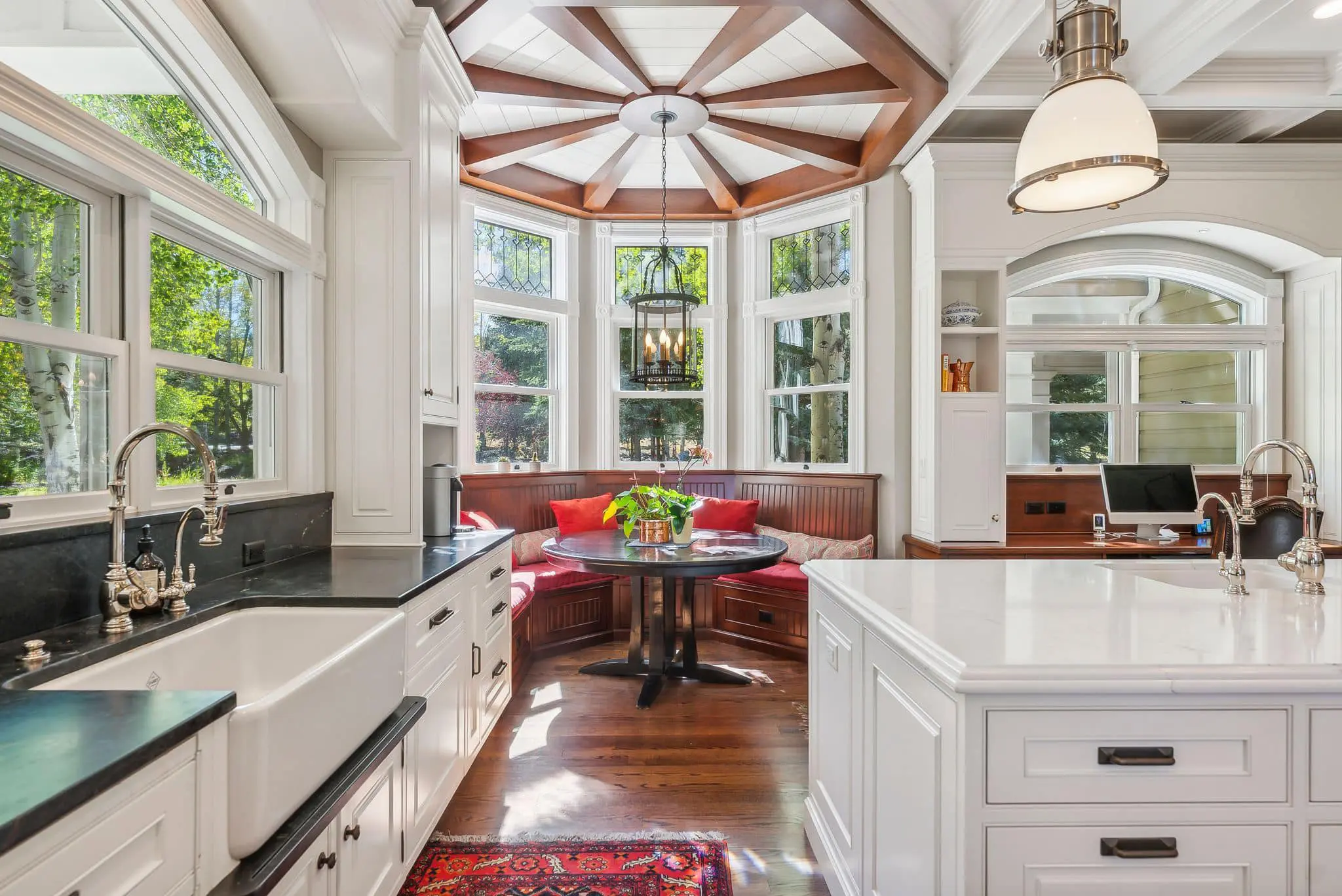 A kitchen with a table and chairs, a bench and a window.