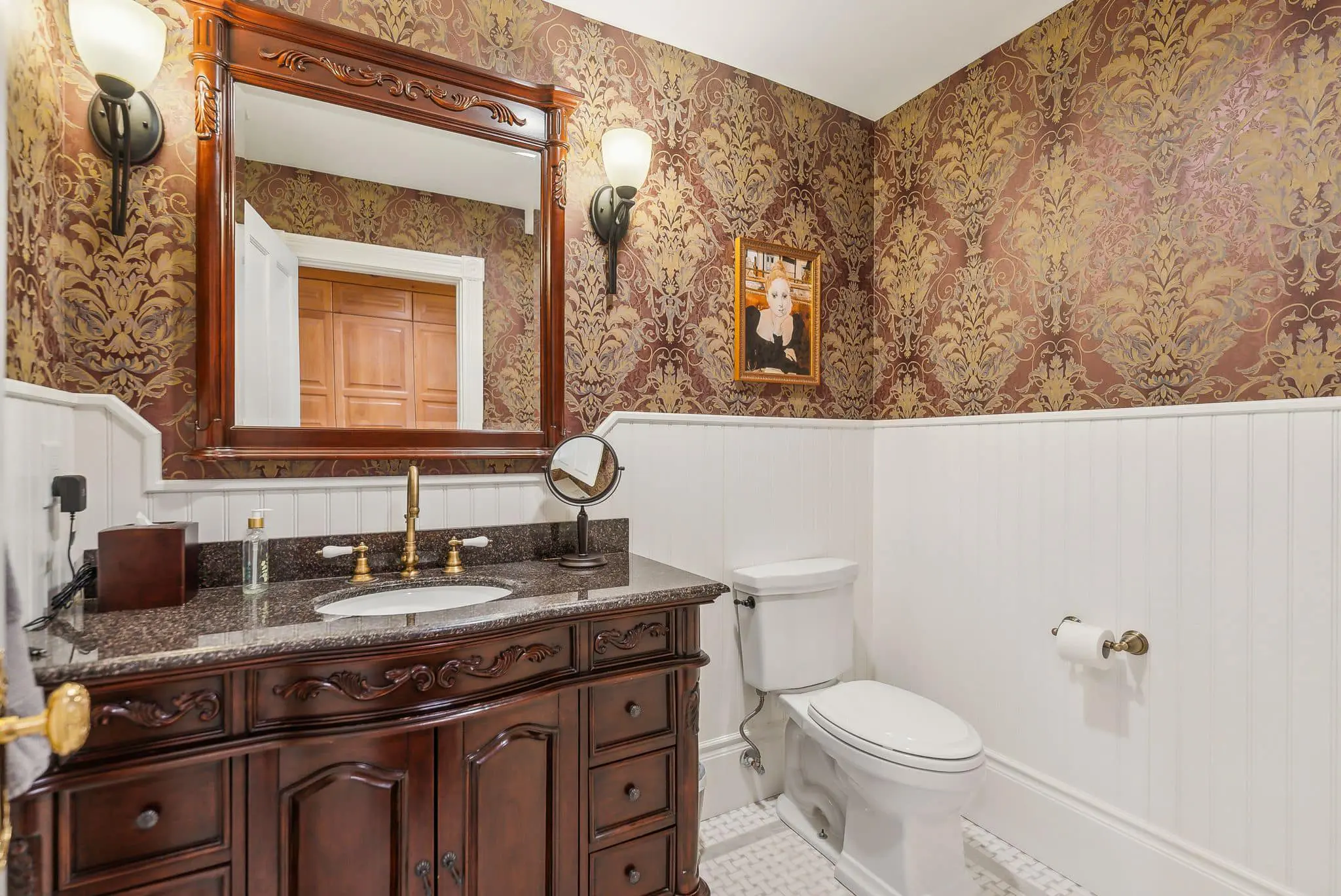 A bathroom with a sink, toilet and mirror.