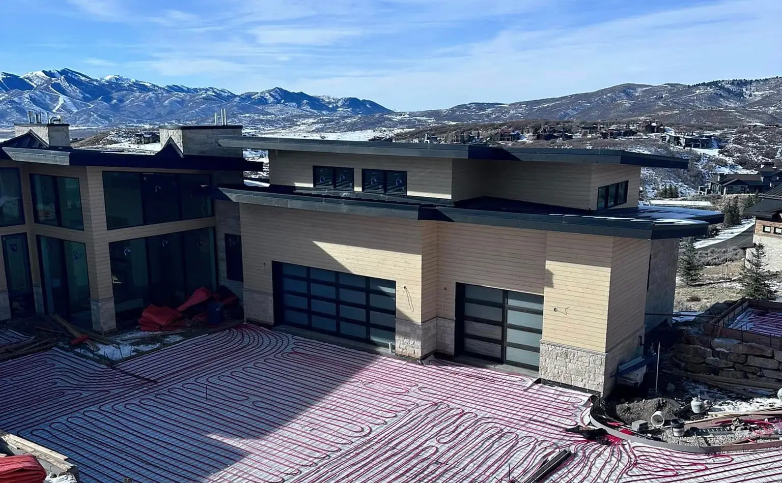 Heated driveway contruction A large house with a garage door and a mountain view.